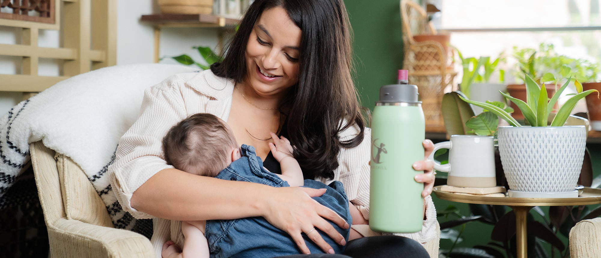 A first-time mom holds her baby to her breast while holding a zen green Chiller.