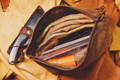An accessory bag with work gloves inside sitting next to a knife on a piece of buckskin