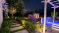 Landscape lighting illuminating garden beds and stepping stone pathways, creating a welcoming connection between outdoor living spaces.