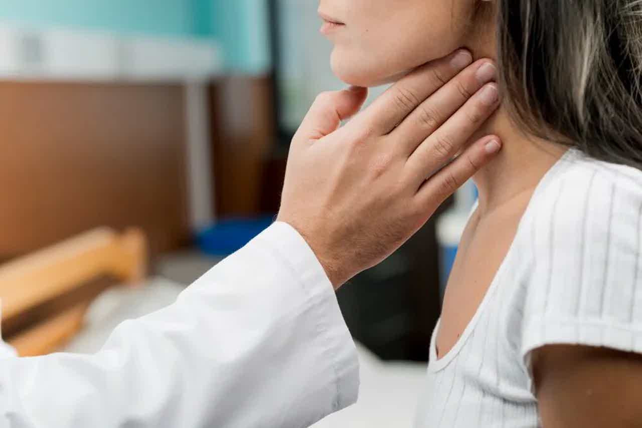 Woman gently touching her jaw and neck with a caring expression, suggesting throat or neck discomfort.