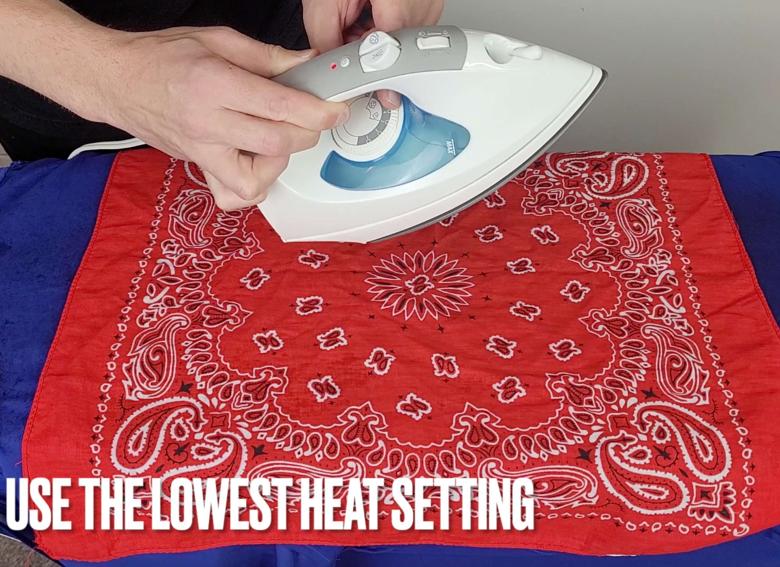 picture of a man holding an iron and adjusting the heat setting to the lowest level