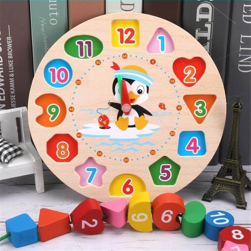 Un jouet puzzle Montessori Penguin Clock coloré avec les chiffres de 1 à 12, conçu pour améliorer la coordination œil-main, avec un pingouin de dessin animé au centre, placé sur un fond de livres empilés et de miniatures E.