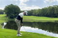 Male golfer addressing the golf ball near water hazard with neutral alignment and stance