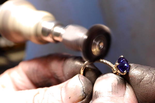 Une bague avec saphir et diamants se fait polir sur une machine à moteur rotatif.