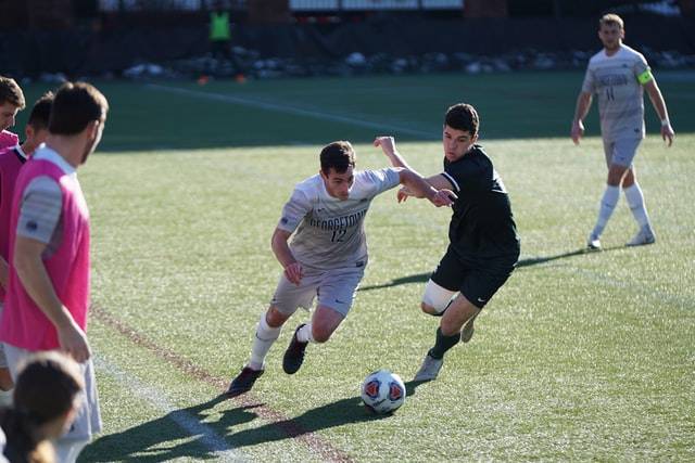 two soccer players fighting for the ball