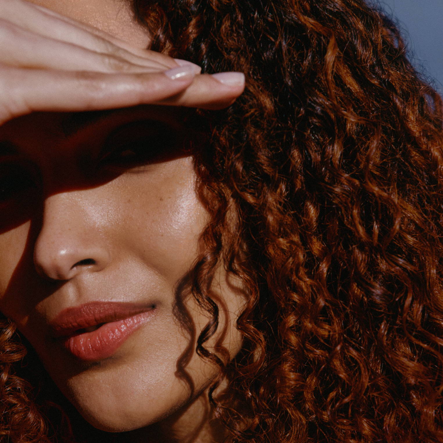 woman with curly brown hair looking into the sunshine