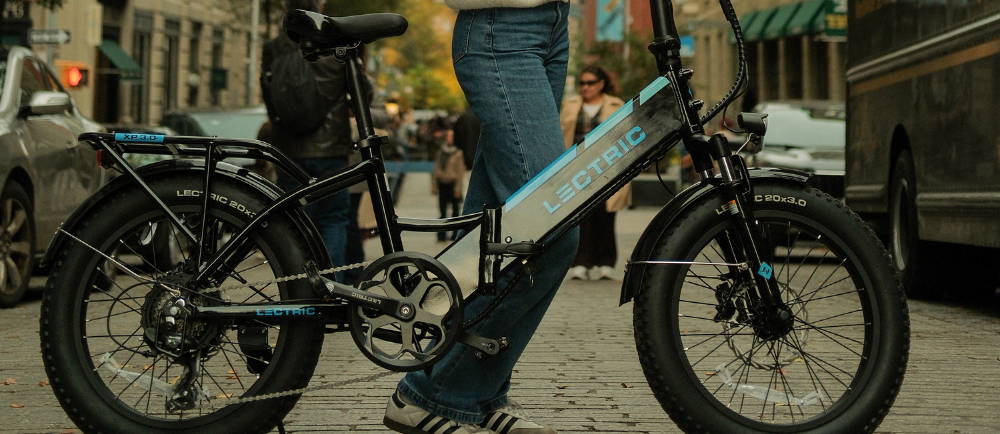 a woman walking next to a lectric electric bike on a city street in new york city
