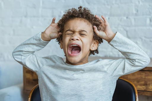 A child with his hands on his head, screaming out in frustration - Photo by Keira Burton from Pexels