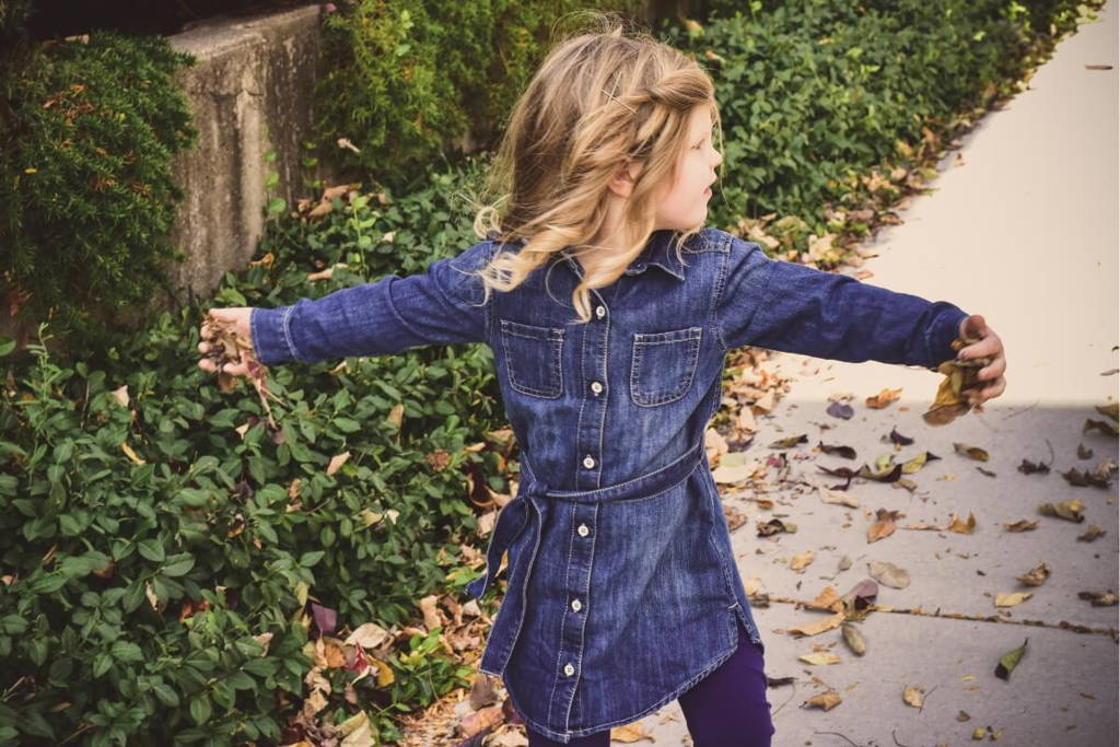 Little girl throwing leaves.