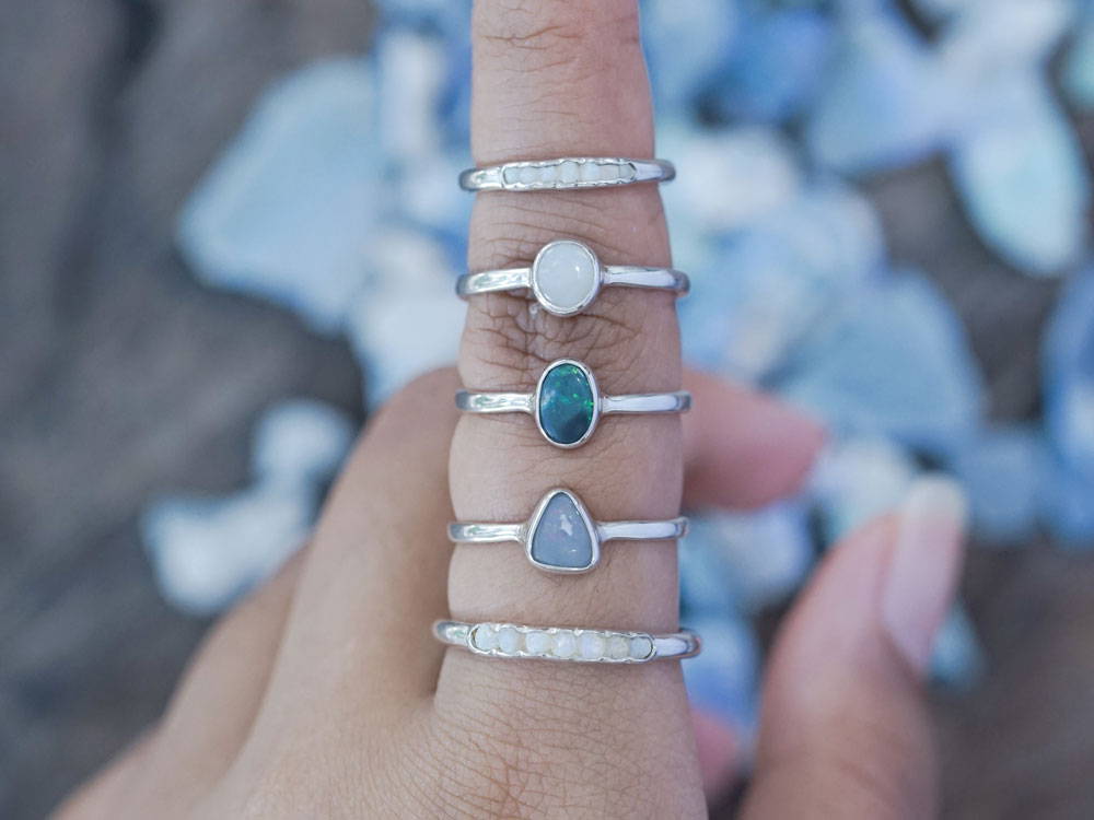 a finger wearing opal ring stack