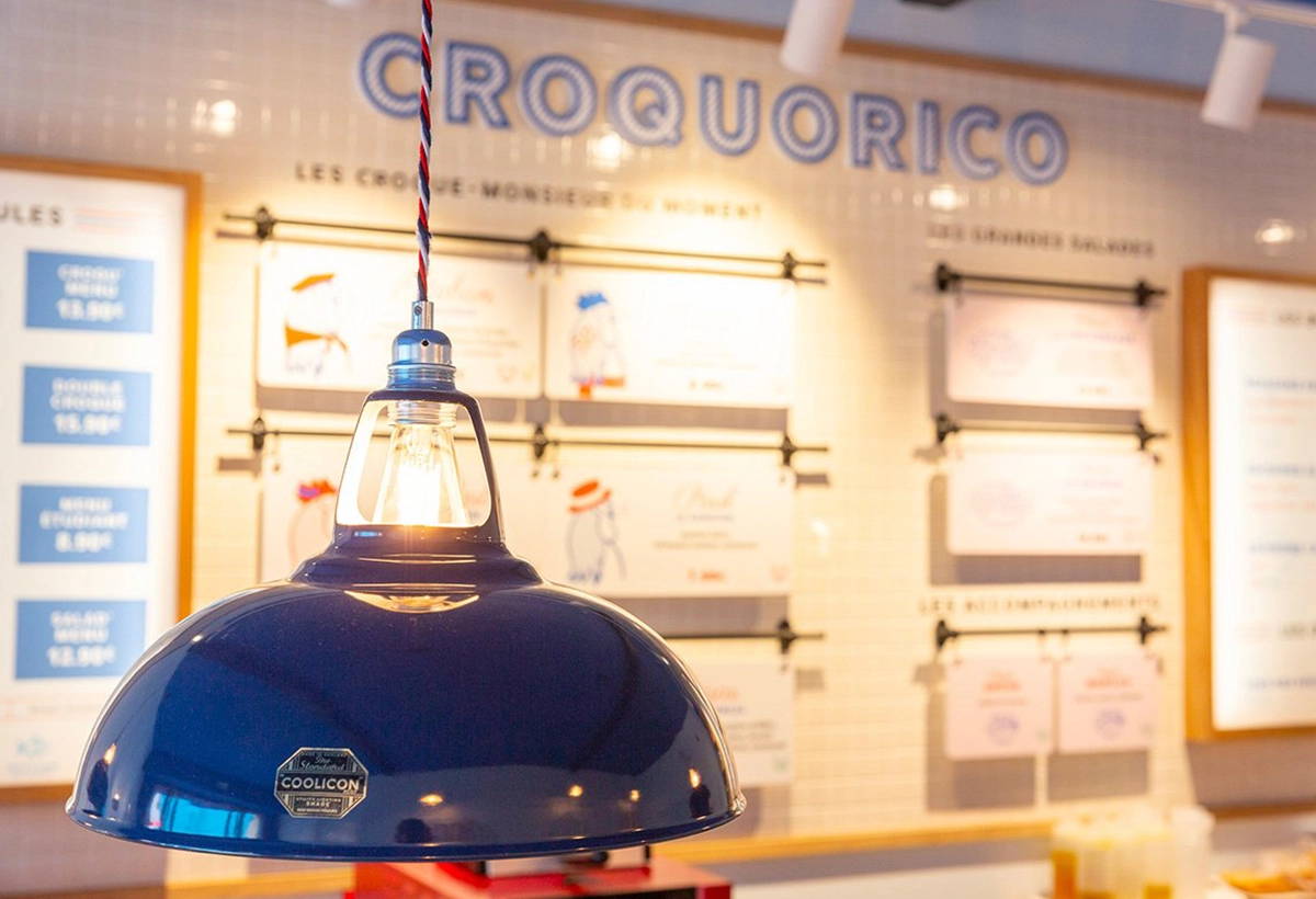 A Large Royal Blue lamp hangs over a wall with a menu in front of the name of the restaurant