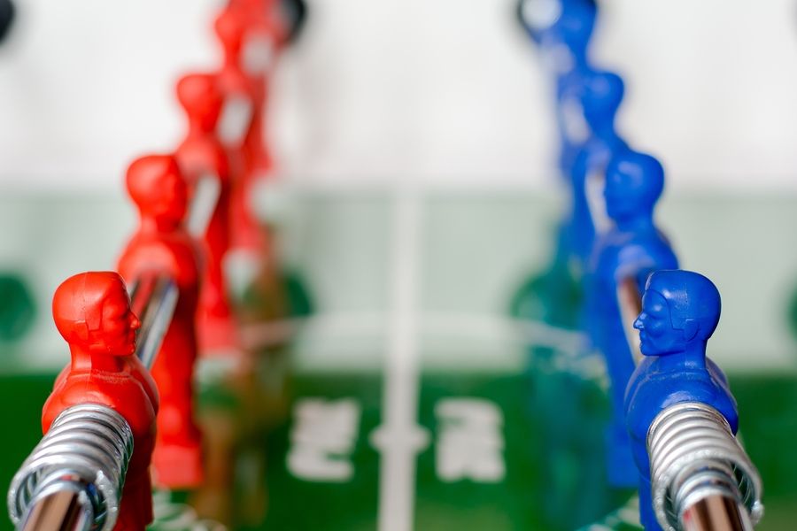 A close up of the mechanical soccer game with two opposing teams, red and blue facing eachother.
