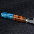 A stunning chef's knife with a vibrant blue and orange handle made of Damascus steel, stabilized wood, and resin.