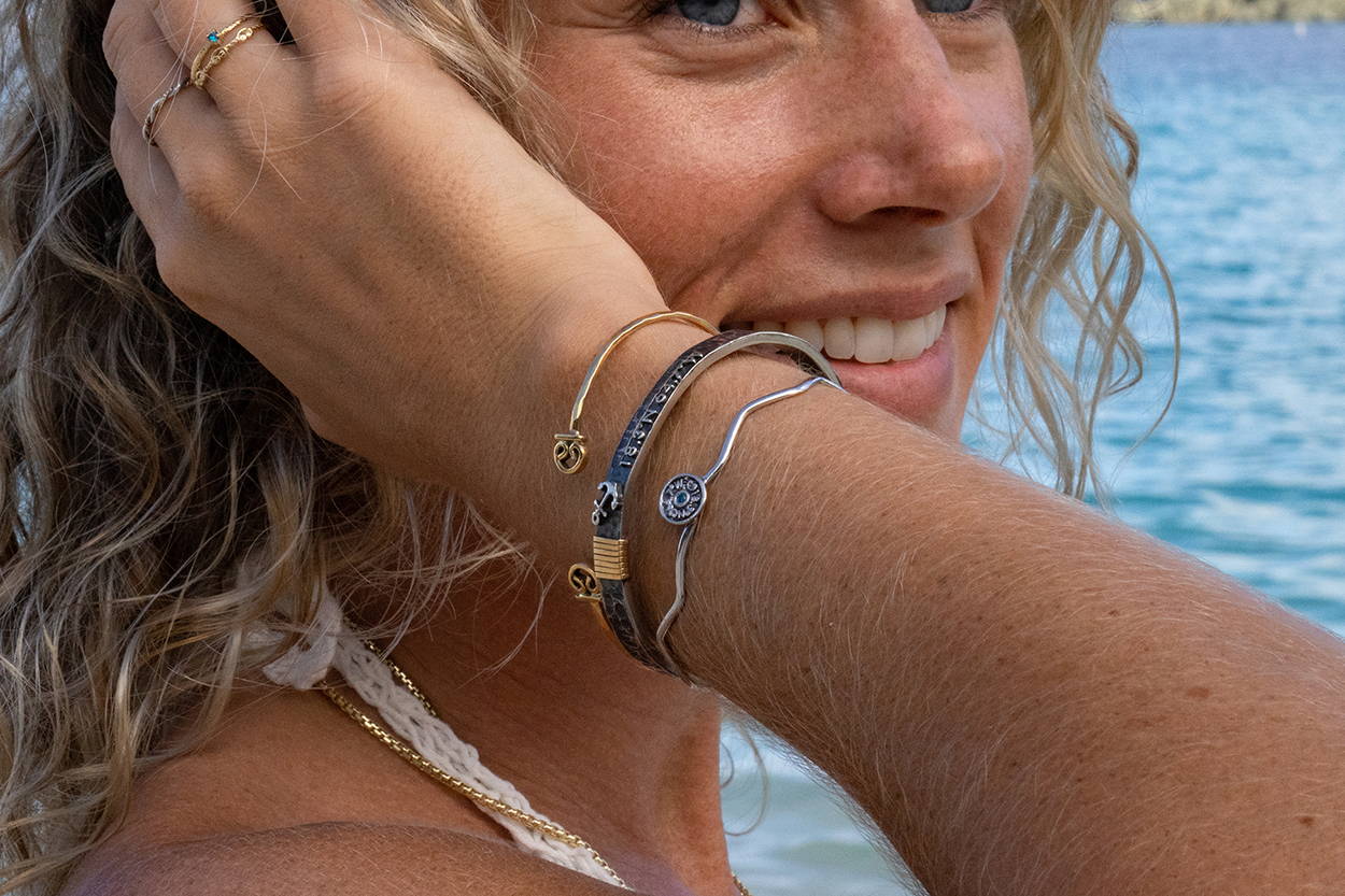 Women brushing her hair behind her ear while wearing Vibe Jewelry bracelets and rings.