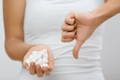 woman in white shirt holding a handful of sugar cubes and giving a thumbs down with her other hand