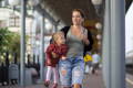 Mother carrying toddler in a busy outdoor setting