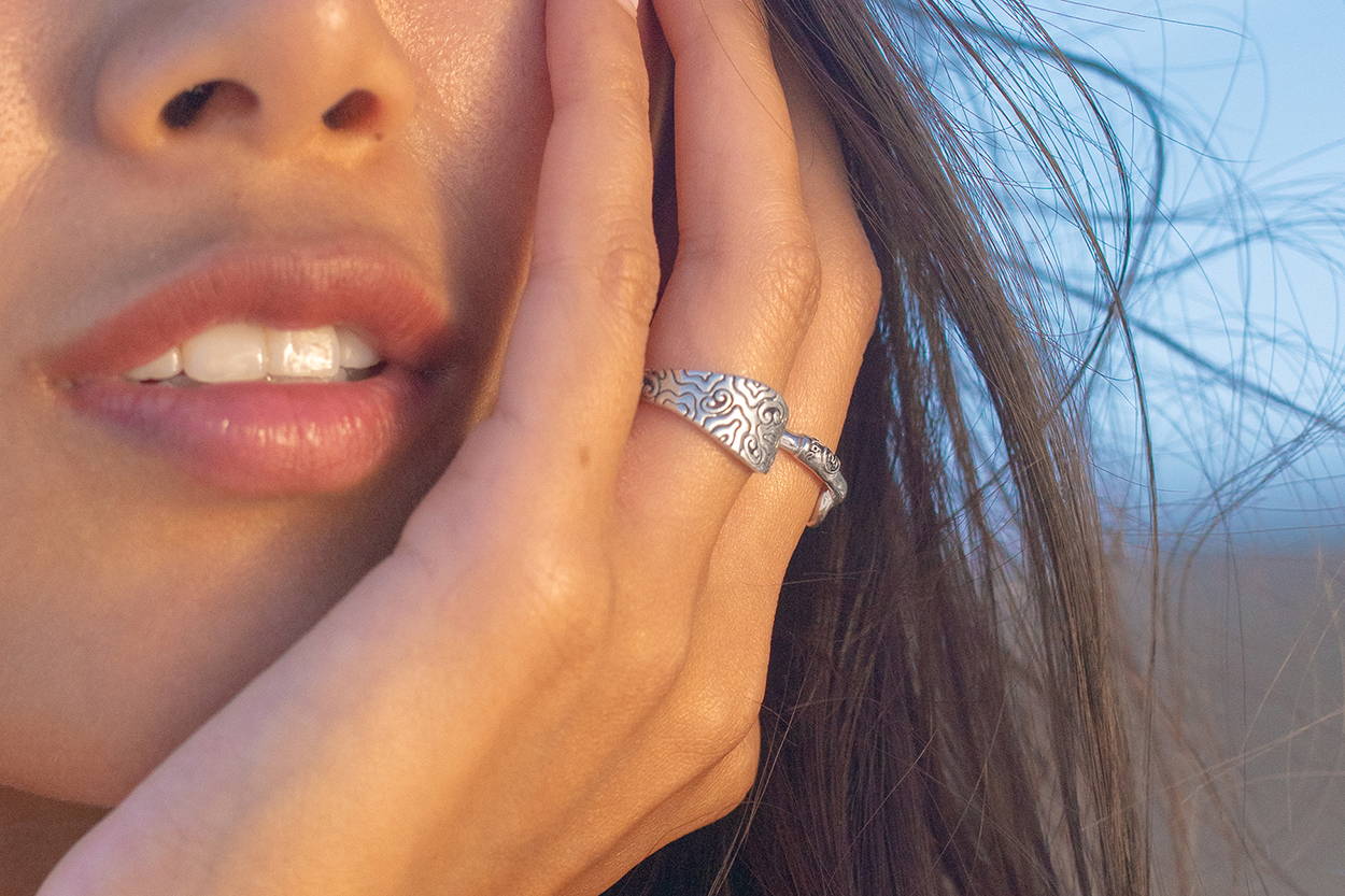 Women with her hand on her face wearing ocean-inspired Vibe Jewelry.