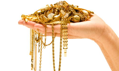 tas de bijoux en or jaune sur la paume d'une main renversée.