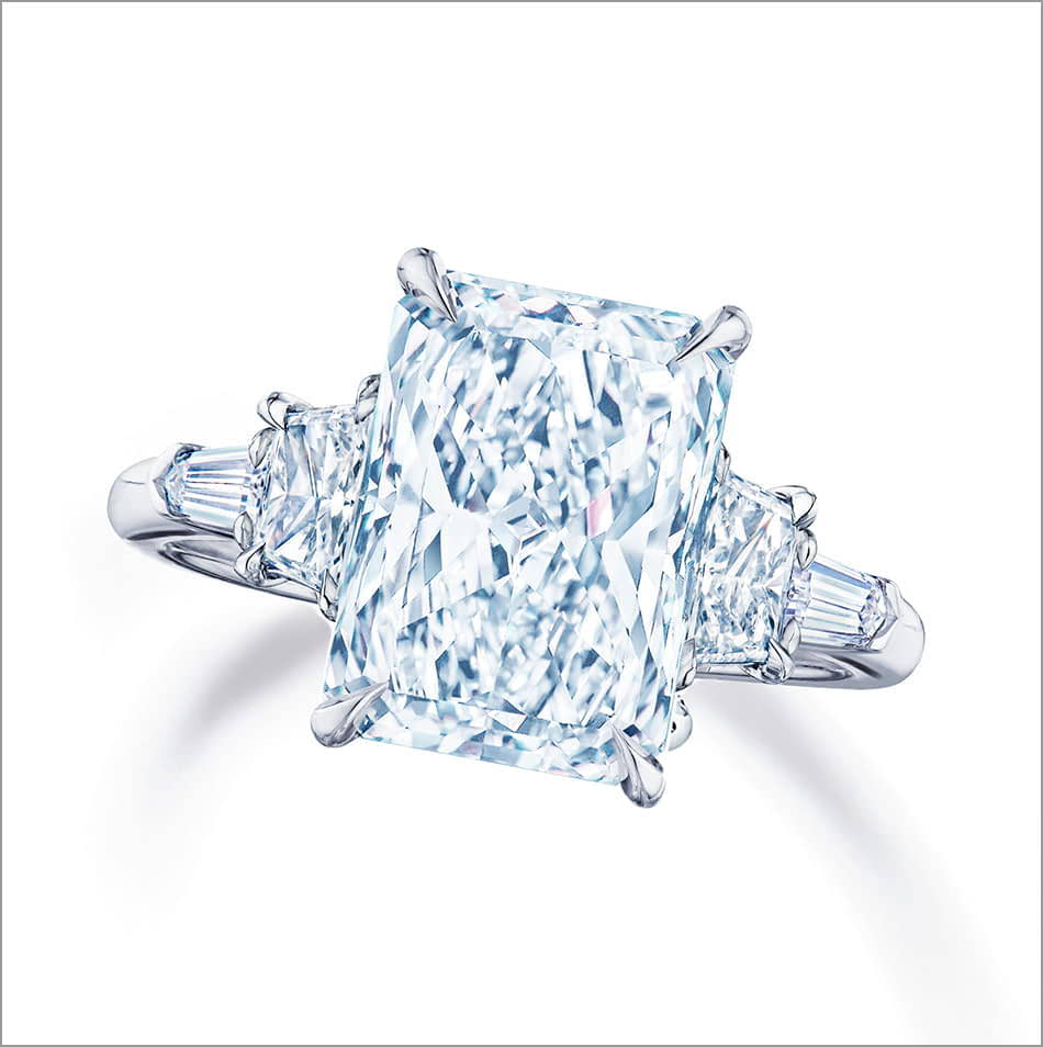 Top view of a Kwiat radiant diamond engagement ring on a white gold band with diamonds. 