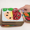 Woman's hand interacting with a children's felt busy book by moving an apple piece revealing yellow beads.