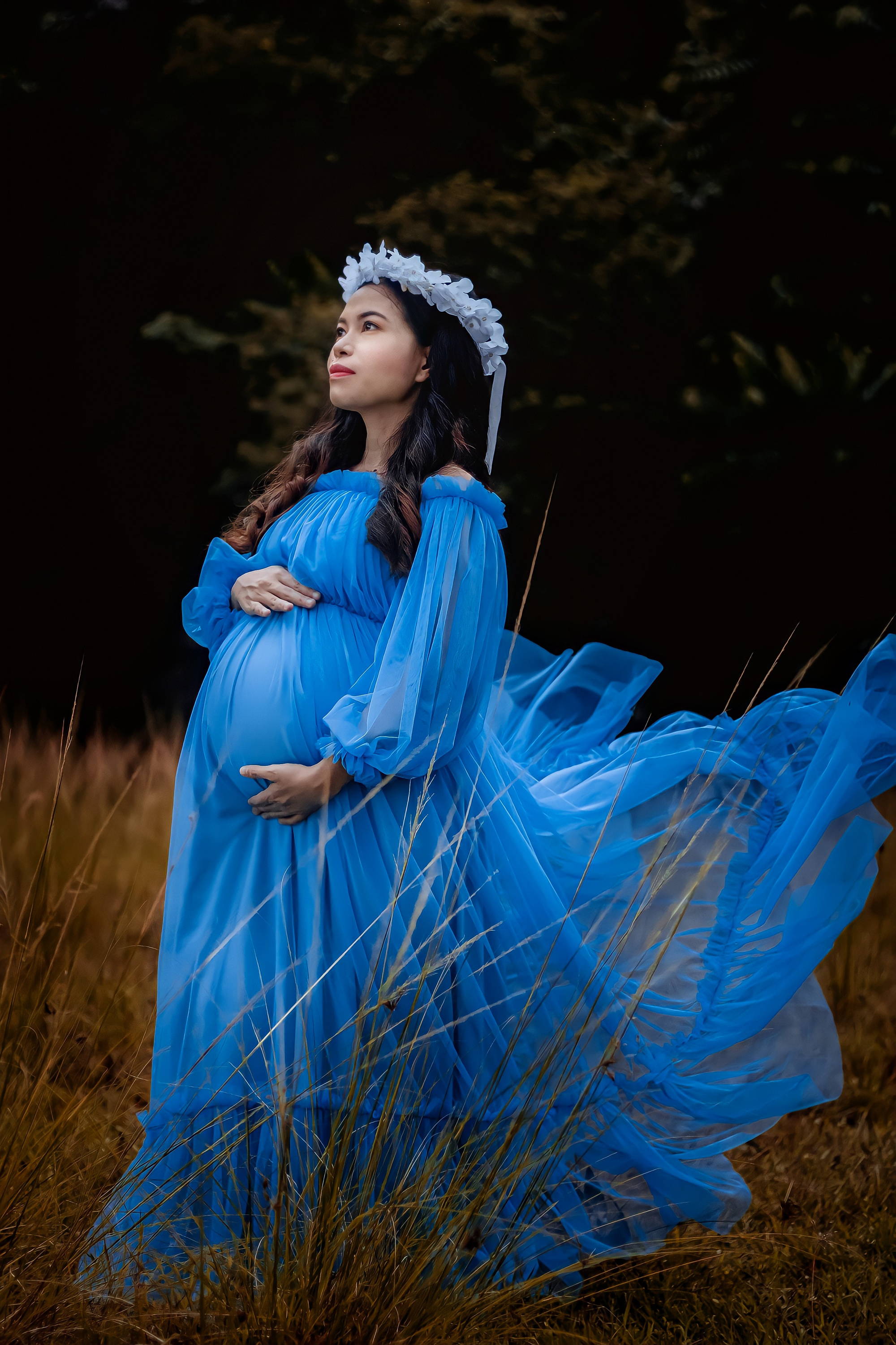 An expectant mom looking all beautiful in a glamorous blue dress