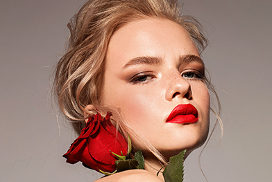 Photo de la jeune fille blonde avec une rose rouge, aux lèvres d'un rouge écarlate.