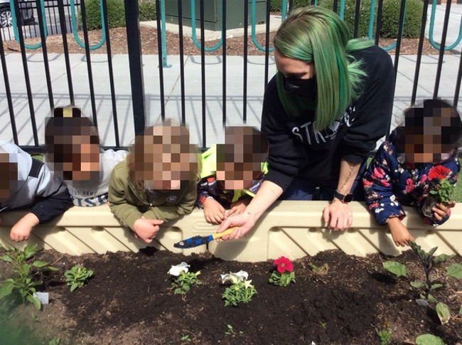 students and teacher planting flowers in the primrose patch garden 