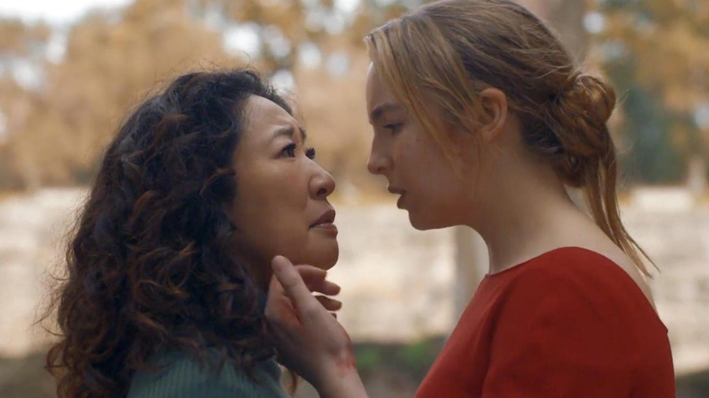 Eve and Villanelle facing one another. Villanelle has a hand lightly touching Eve's chin.