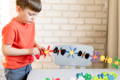 Baby putting a decoration on a birthday cake.