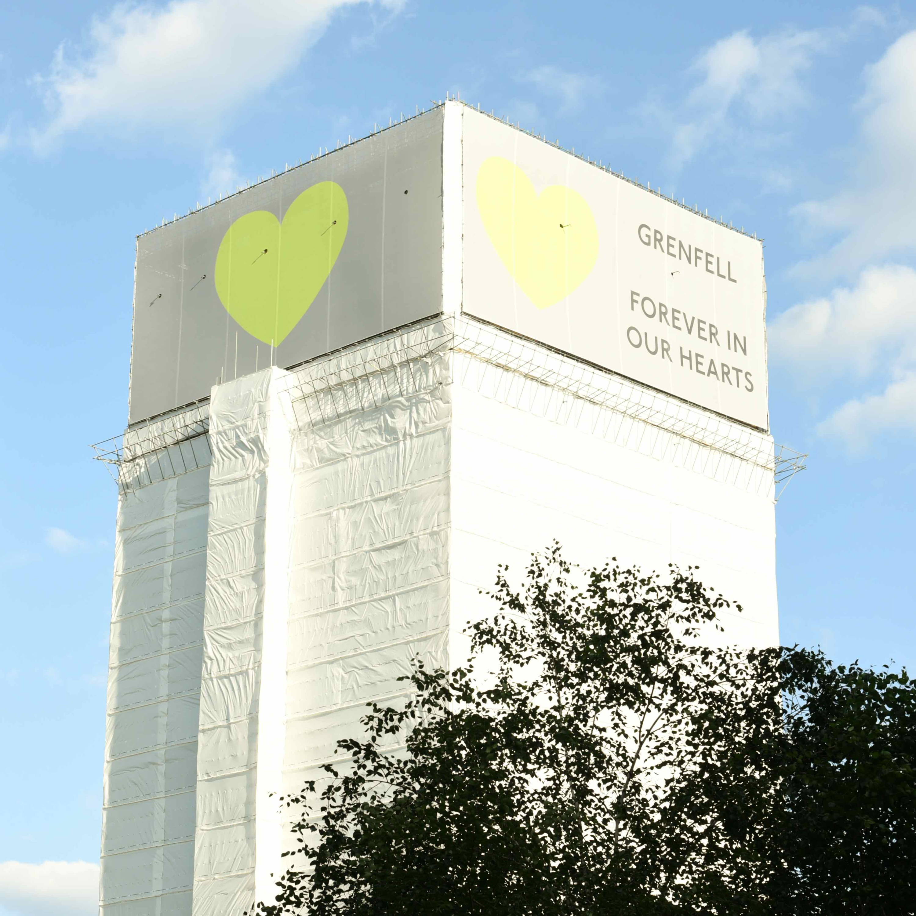 Grenfell Tower with sign reading: forever in our hearts