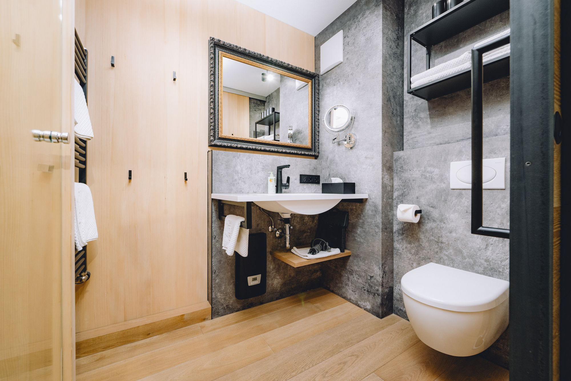 Ein modernes Badezimmer mit Stein- und Holzwänden, Wandheizung und einem eingerahmten Spiegel.