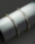 Pair of sleek gold bangles embellished with baguette diamonds, displayed on a smooth cylinder against a dark grey backdrop.