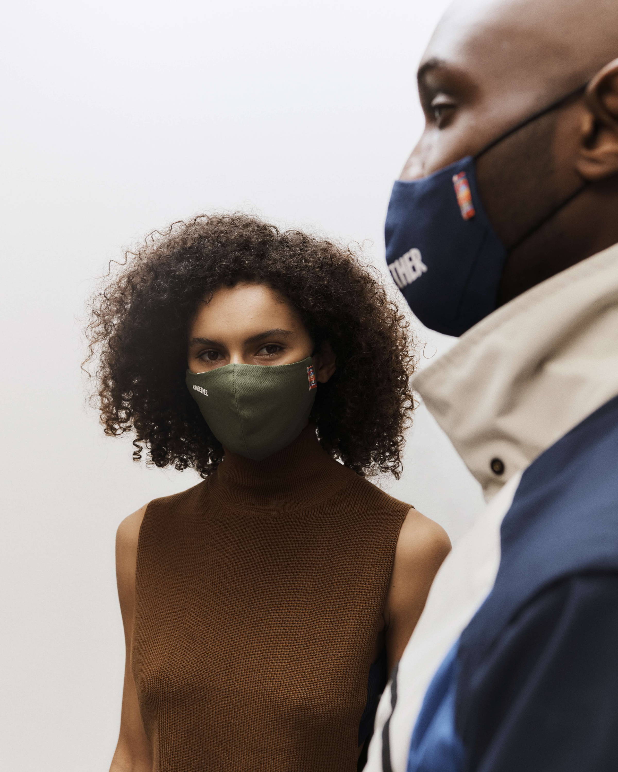 A man and a woman model wear olive green and navy blue organic cotton face masks