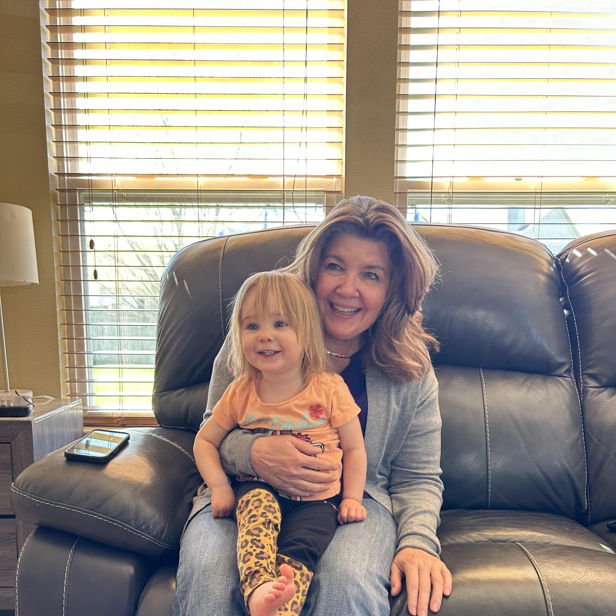 A woman and a smiling child share a warm, cozy moment on a sofa, highlighting their close bond and joy together.