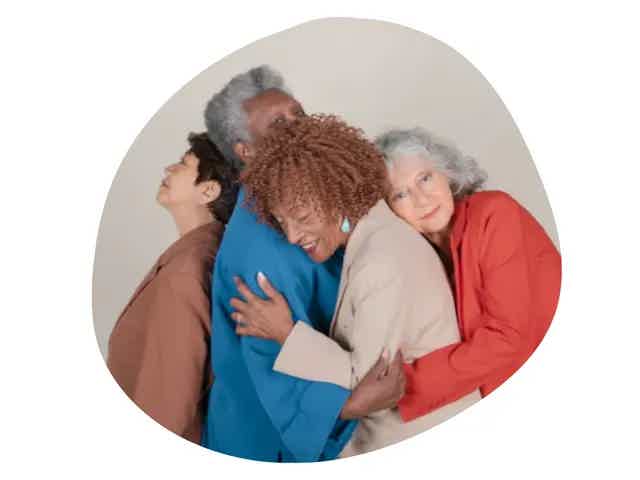 Group of four diverse seniors embracing in a warm hug inside an irregular oval shape.