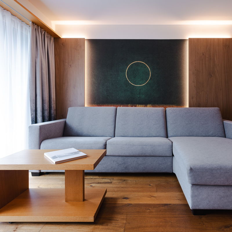Suite mit grauem Sofa und Bar im Hintergrund