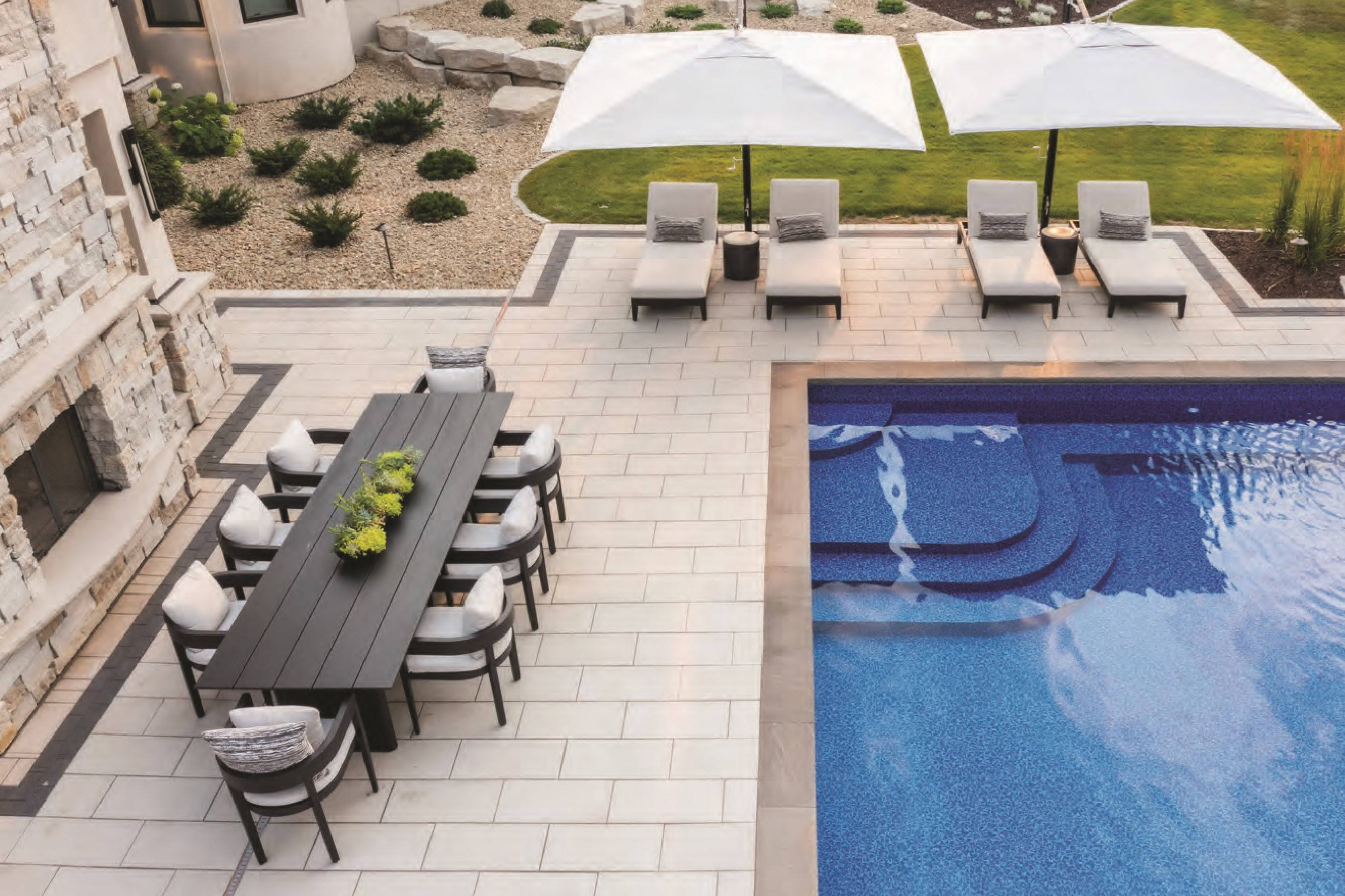 Poolside patio made with Grand Discover XL Pavers with a seating area and dining area.