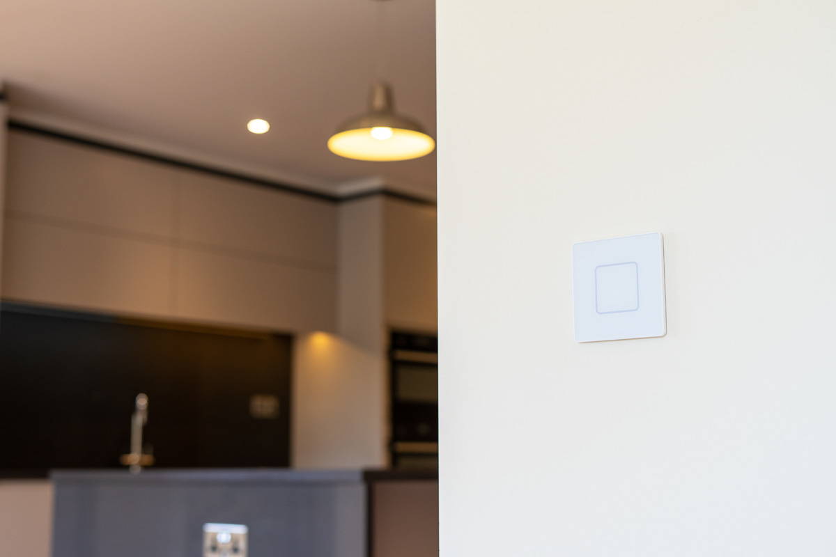 Faradite single gang TAP light switch in matt white on a kitchen wall.