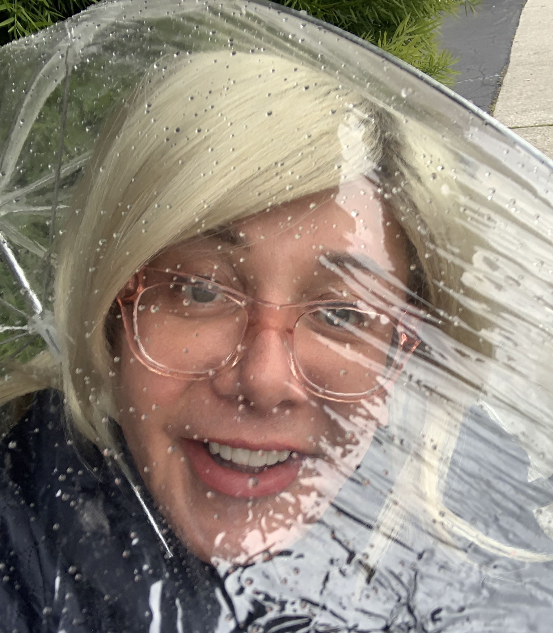 Isabel smiling through a see through umbrella.