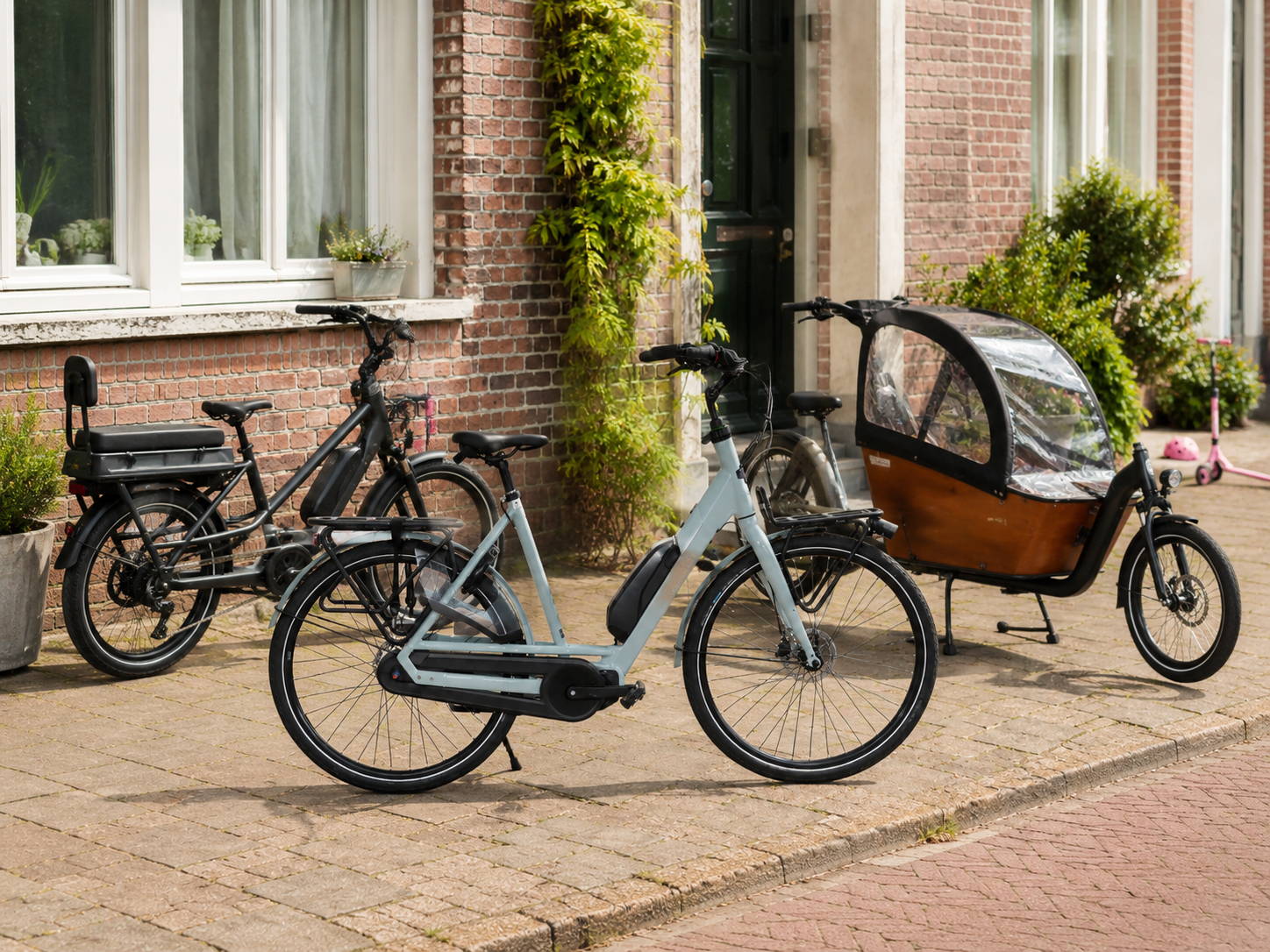 Elektrische moederfiets, longtail e-bike en bakfiets voor een woonhuis als vergelijking van familiefietsen voor dagelijks gezinsgebruik.