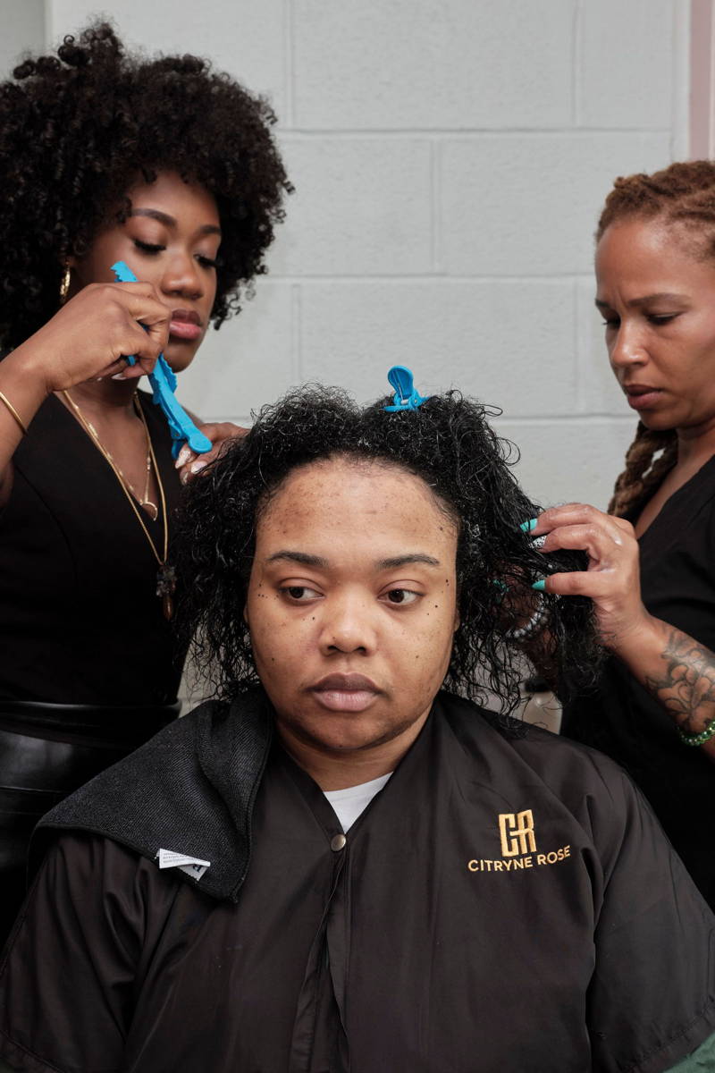 Daesha Holloman getting her hair done by two women