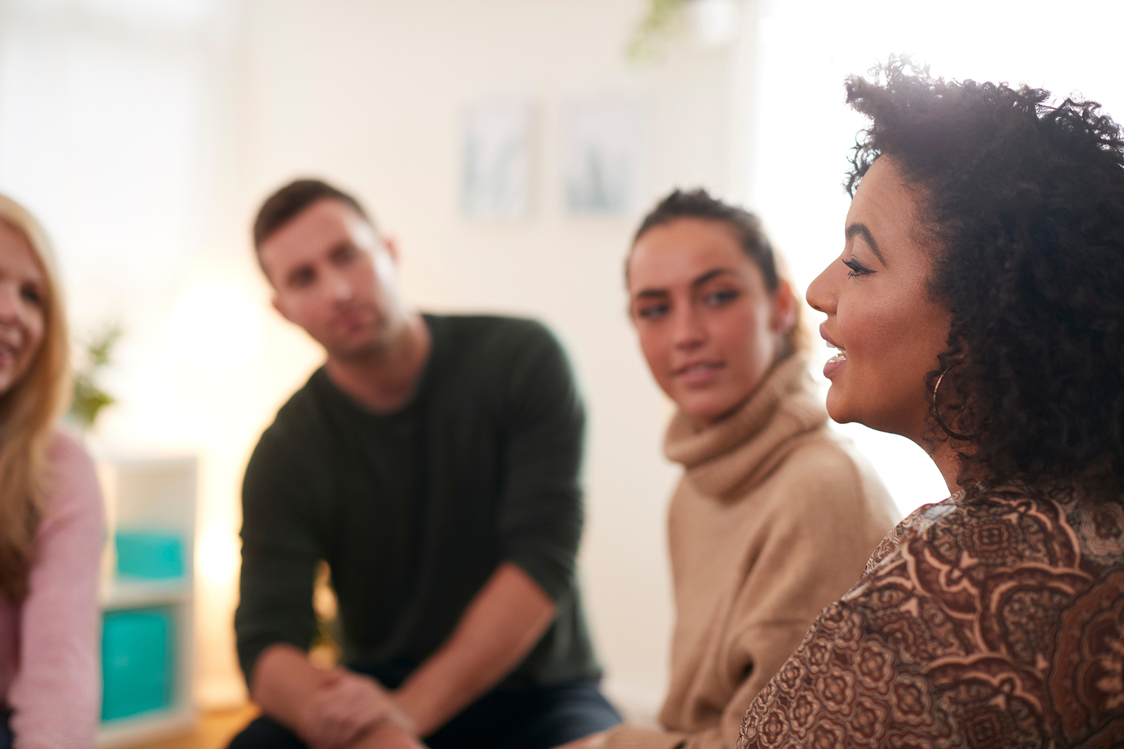 A black woman woman talking in a therapy circle smiling.