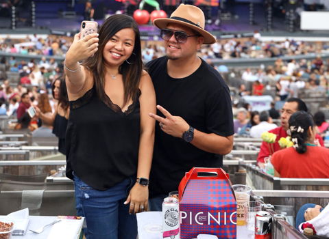 Concert-goers take a selfie in front of the Bowl shell with their Food + Wine picnic box