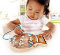 Little girl playing with the Montessori Fish shaped Magnetic Maze and moving the magnetic ball around it. 