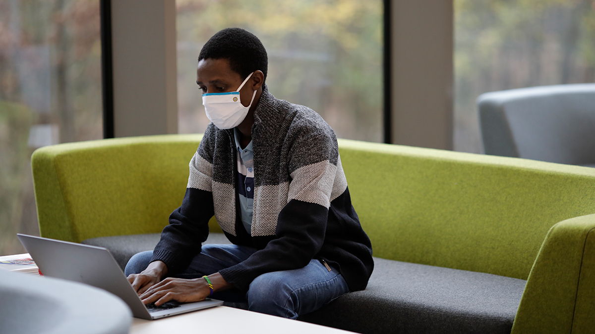 A student wearing mask using a laptop
