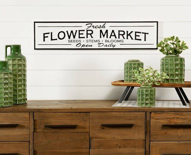wooden console table with set of green ceramic containers and black and white flower market sign