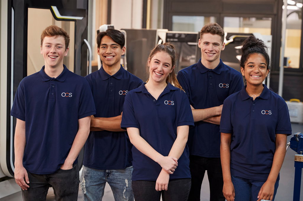 Group of diverse young people smiling wearing OCS logo polo shirts.