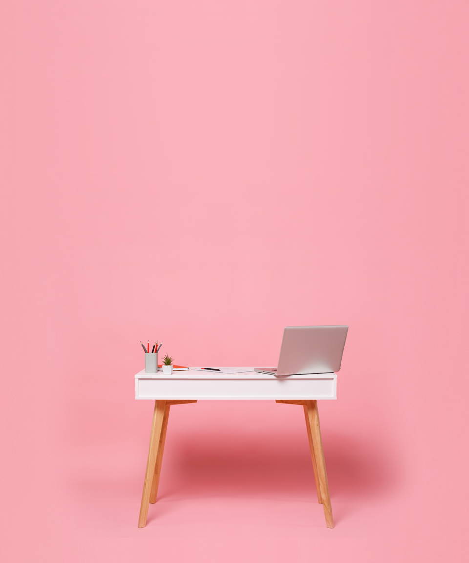 Desk with a laptop and office supplies against a pink background (small)
