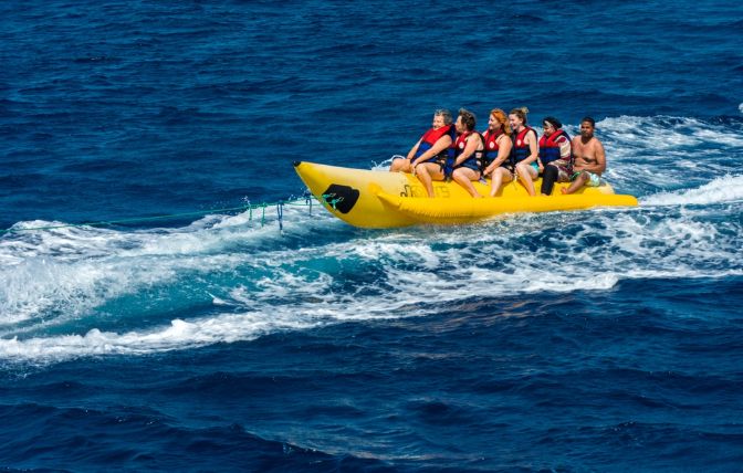 Egypt, Sahl Hasheesh October, 03, 2019. Tourists have fun and enjoy riding on a red and white inflatable banana that carries a scooter across the sea. The concept of summer holidays, vivid impressions