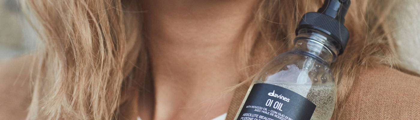 close-up of blonde hair woman holding Davines OI Oil